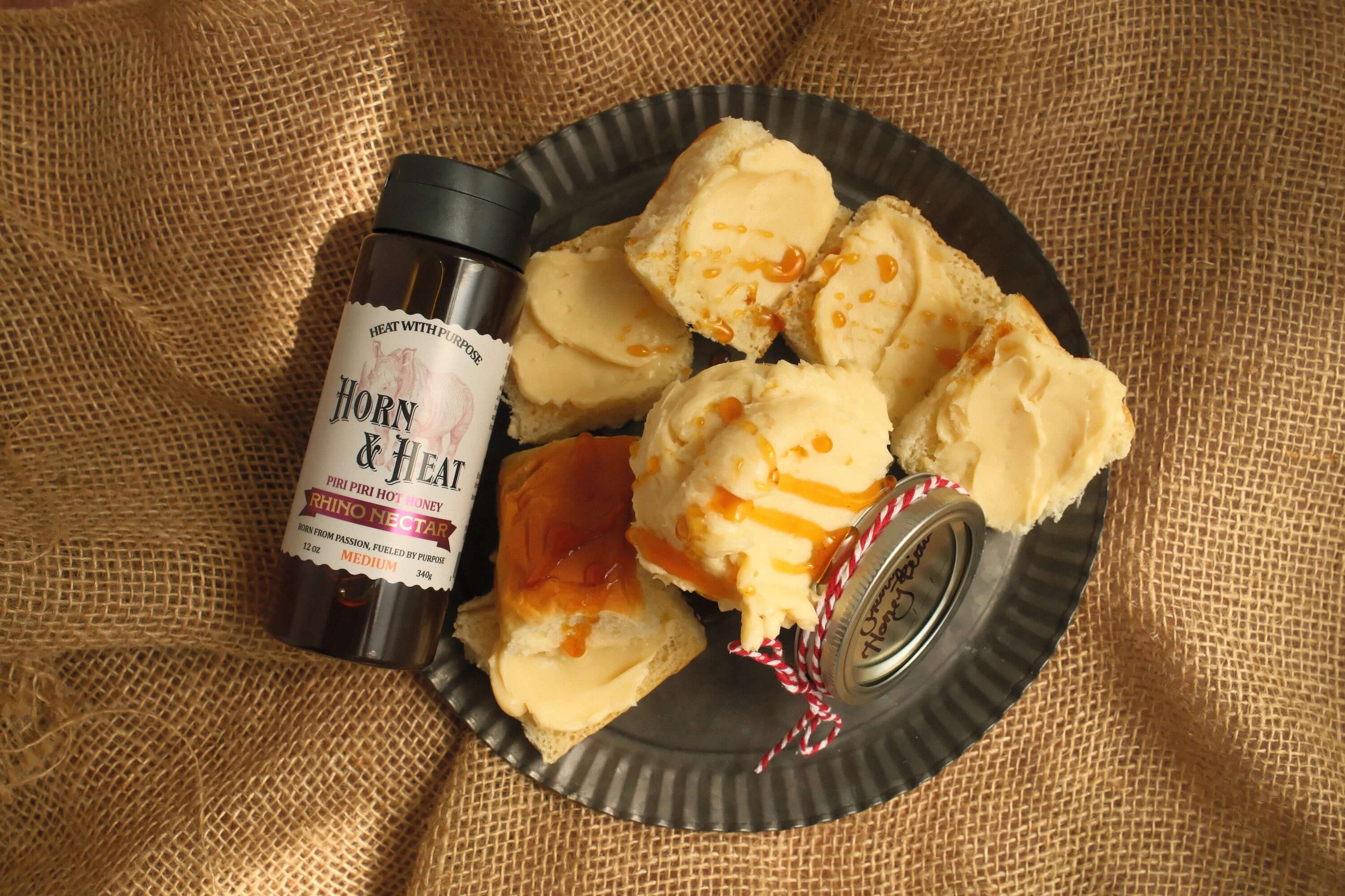 Rhino Nectar Whipped Hot Honey Butter displayed on a tray with a bottle of Horny & Heat sauce.