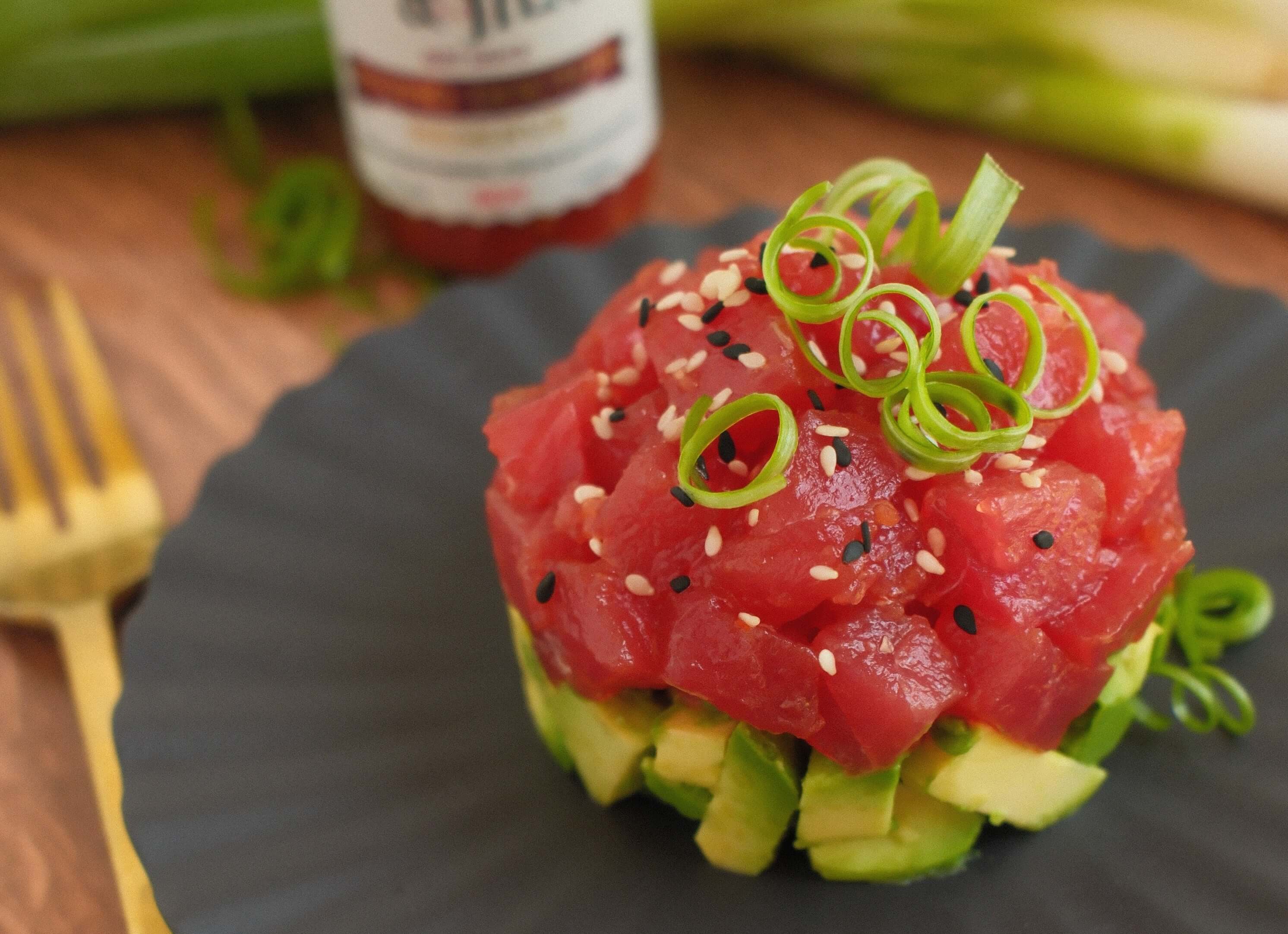 Horn & Heat Tuna Tartare with Rhino Doctor Reserve served on a black plate, garnished with green onions.