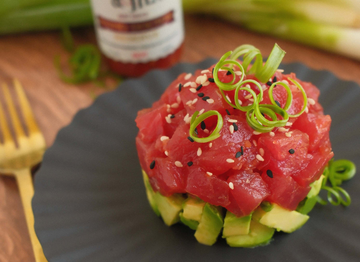 Horn & Heat Tuna Tartare with Rhino Doctor Reserve served on a black plate, garnished with green onions.