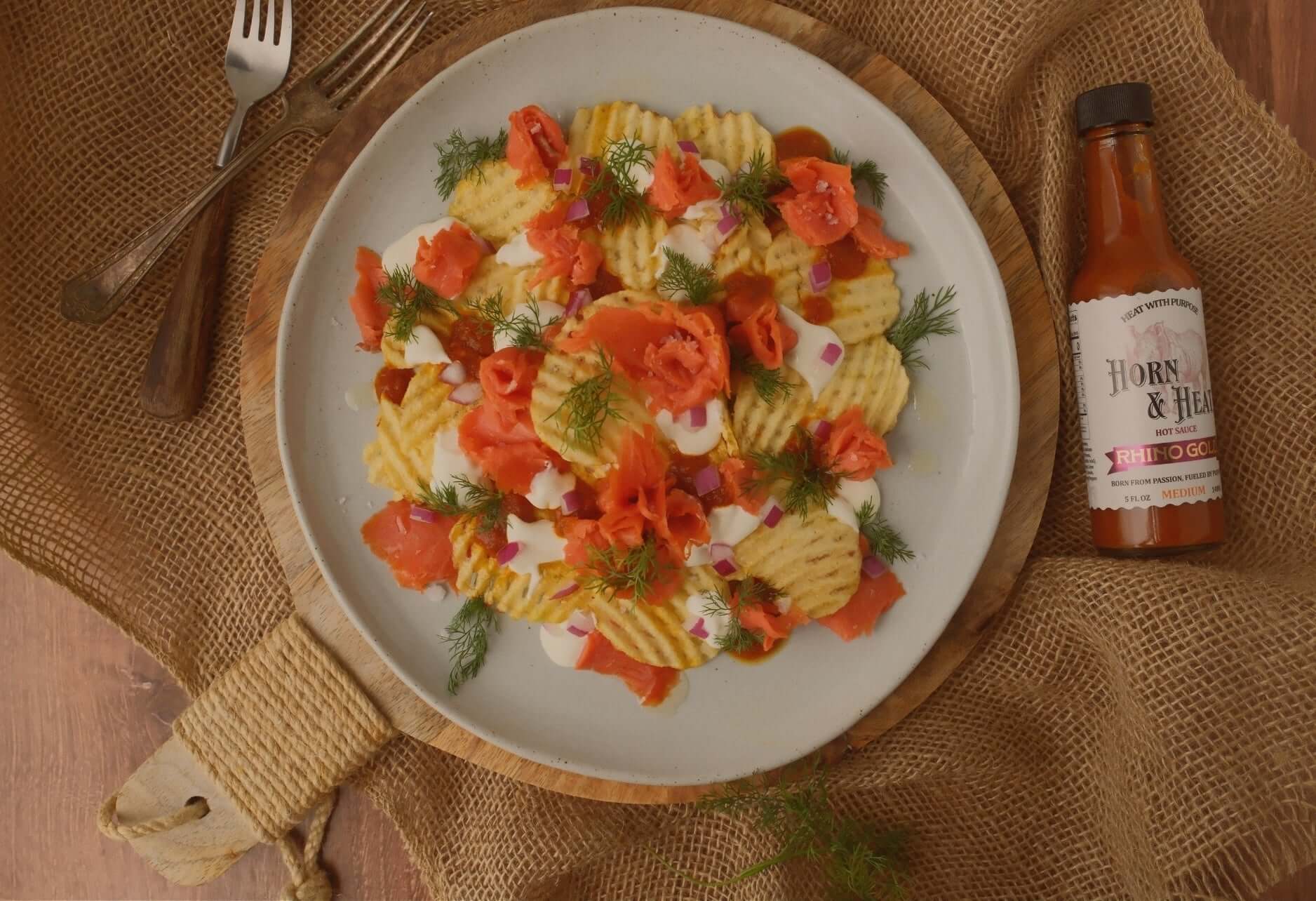 Horn & Heat Nachos with Rhino Gold Hot Sauce served on a rustic plate with fresh toppings.